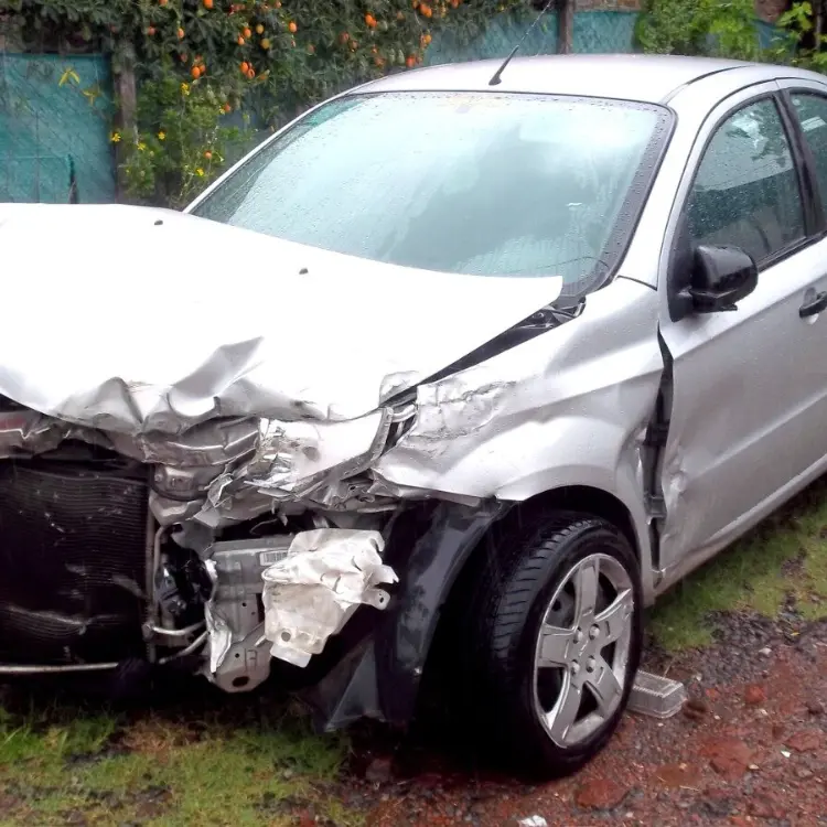 Vehículo plateado con fuerte daño frontal bajo la lluvia; ejemplo para compramos autos chocados de AutoEfectivo con retiro en grúa y pago trazable.