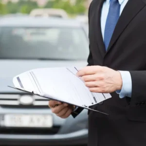 Asesor revisando contrato frente a vehículo; proceso para vender mi auto usado y vender automóvil usado con AutoEfectivo: cotización online, retiro y pago en 72 h.